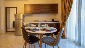 Cocina moderna con armarios de madera, horno empotrado y comedor con mesa y sillas redondas.