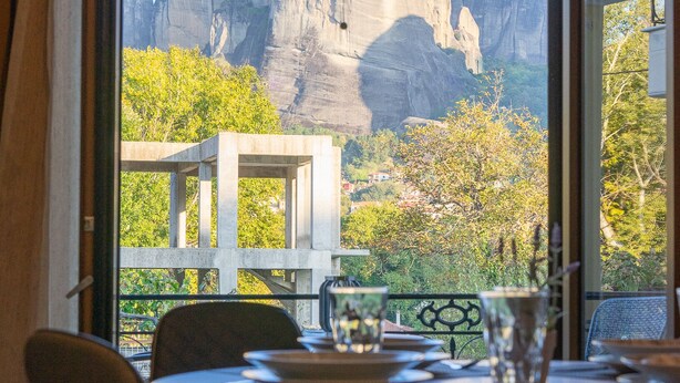 Comedor con mesa y sillas, vista de una montaña y un edificio al fondo.