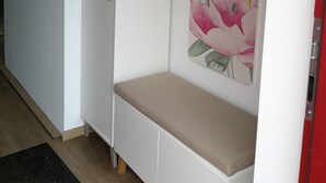 A room with a white bench, a red door, and a floral painting on the wall. - Ferienwohnung Ranunkel (Beilngries)