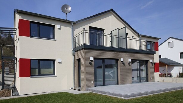 A modern two-story house with a balcony, large windows, and a satellite dish. - Ferienwohnung Ranunkel (Beilngries)