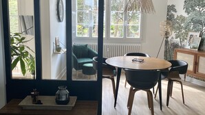 A modern dining area with a round table, chairs, and a hanging light fixture.