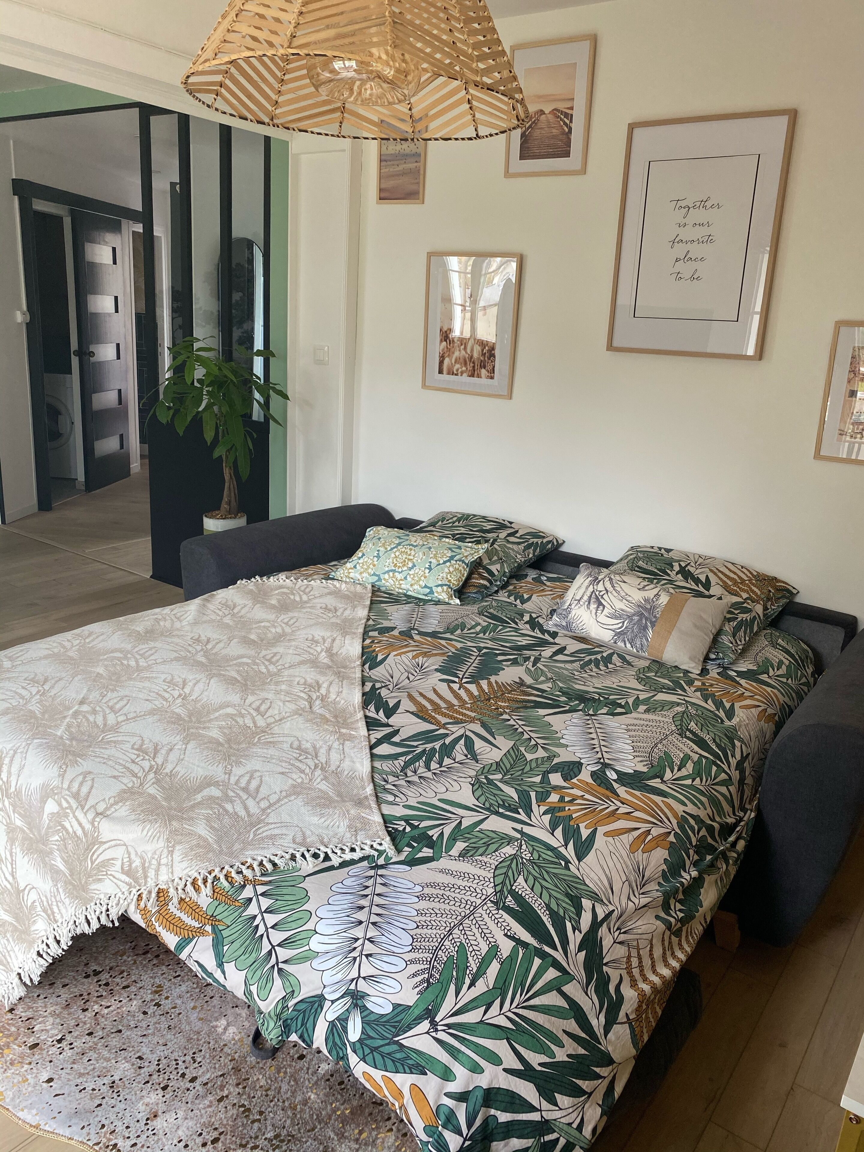 Een slaapkamer met een bed, een hanglamp en ingelijste foto's aan de muur.