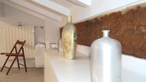 A kitchen with white countertops, a wooden chair, a large vase, and a metal container.