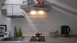 A modern kitchen with a stainless steel sink, a kettle, and a coffee maker on the counter.