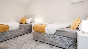 Een moderne slaapkamer met twee bedden, een nachtkastje en een bedlampje.