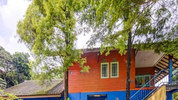 A two-story building with a red and blue facade, a visible staircase, and a green door. - Spot ON 90046 Villa Anyelir Yustik Selabintana (Sukabumi)