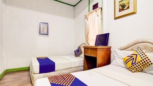 A hotel room with two beds, a wooden nightstand, a desk with a computer, and a framed picture on the wall. - Spot ON 90046 Villa Anyelir Yustik Selabintana (Sukabumi)
