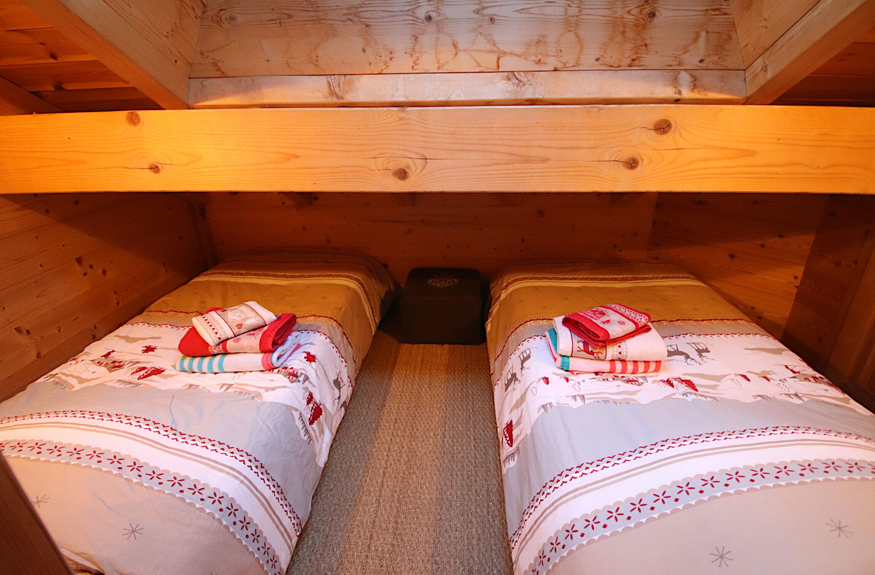 A wooden cabin with two beds, each with a patterned bedspread and pillows.