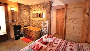 Un dormitorio con pared de piedra, puerta de madera y una cama grande con ropa de cama estampada.