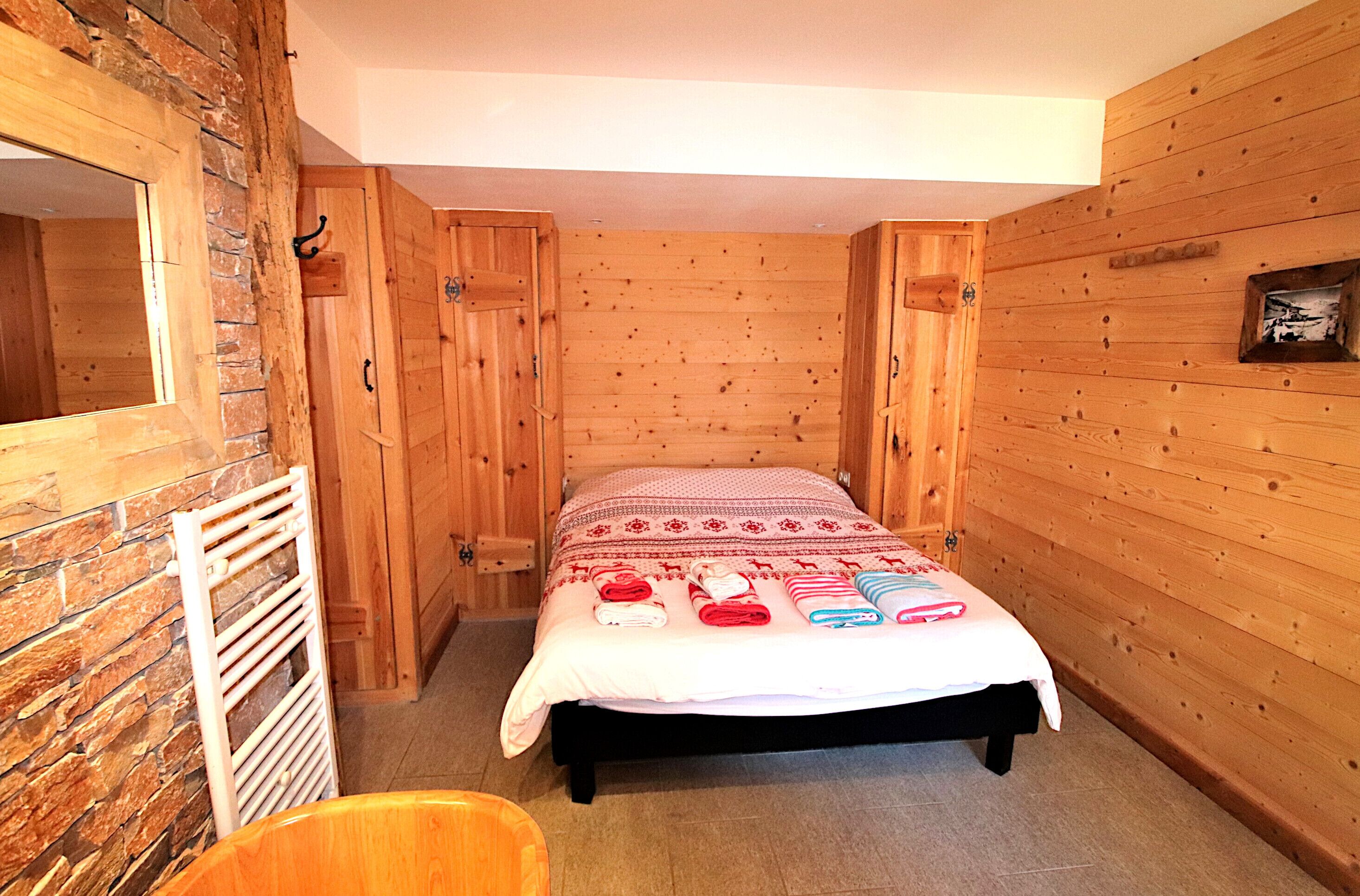 A wooden-paneled room with a bed, a radiator, and a small framed picture on the wall.