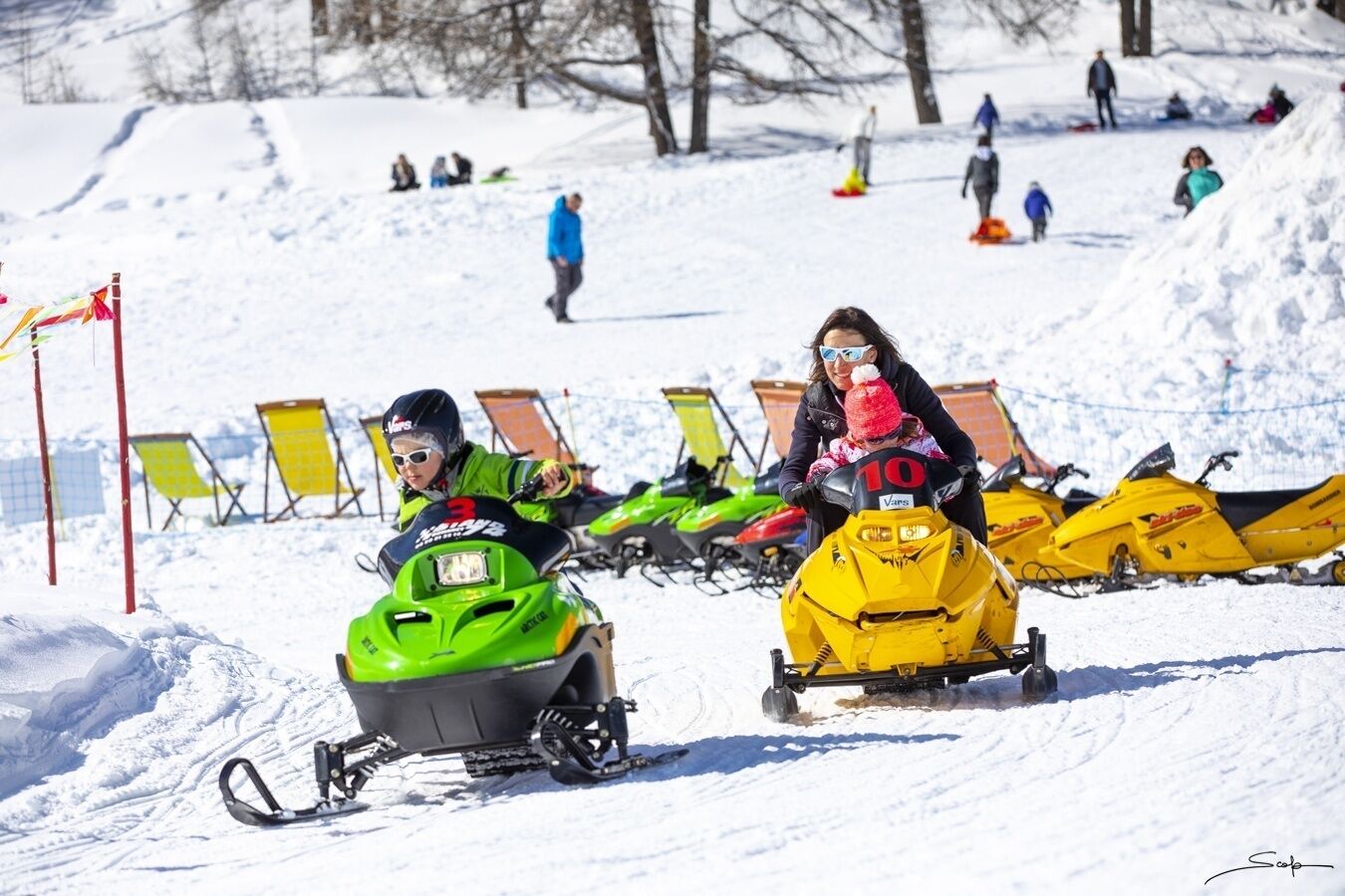 Pista de motos de neve com pessoas a andar e outras a caminhar ao fundo.