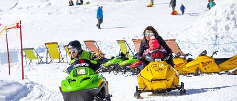 Pista de motos de neve com pessoas a andar e outras a caminhar ao fundo.