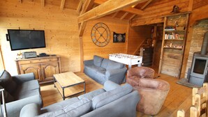 Un interior acogedor de madera con televisión de pantalla plana, sofás, un dardo y una chimenea.