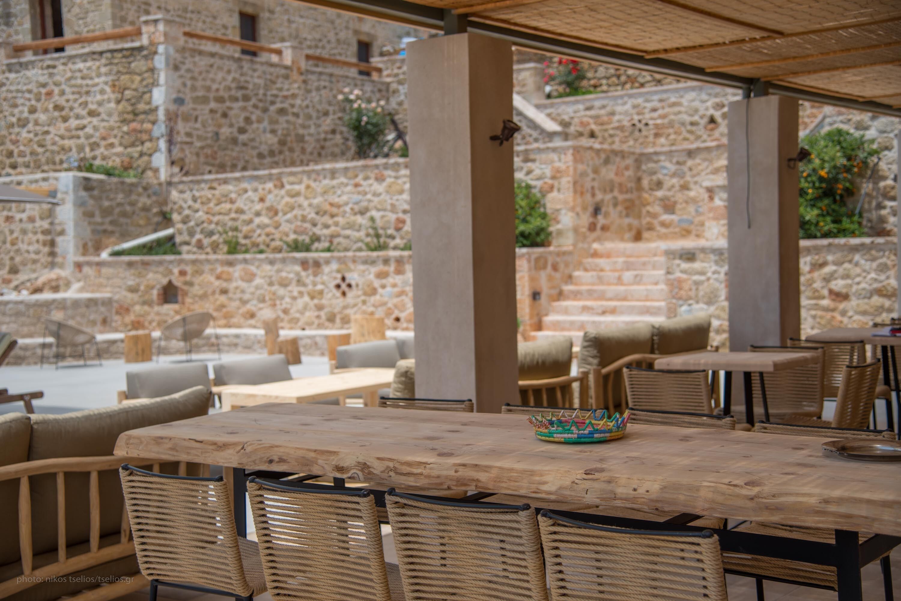 An outdoor seating area with stone walls and wooden furniture.