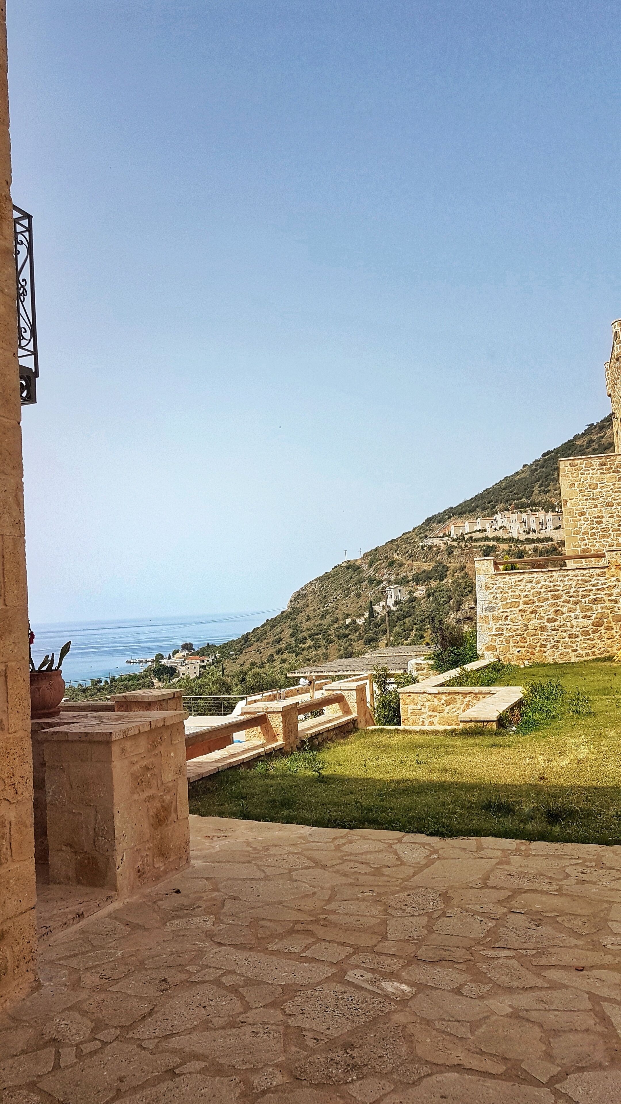Ein Steinhaus mit Blick auf das Meer und eine Hügelkuppe.