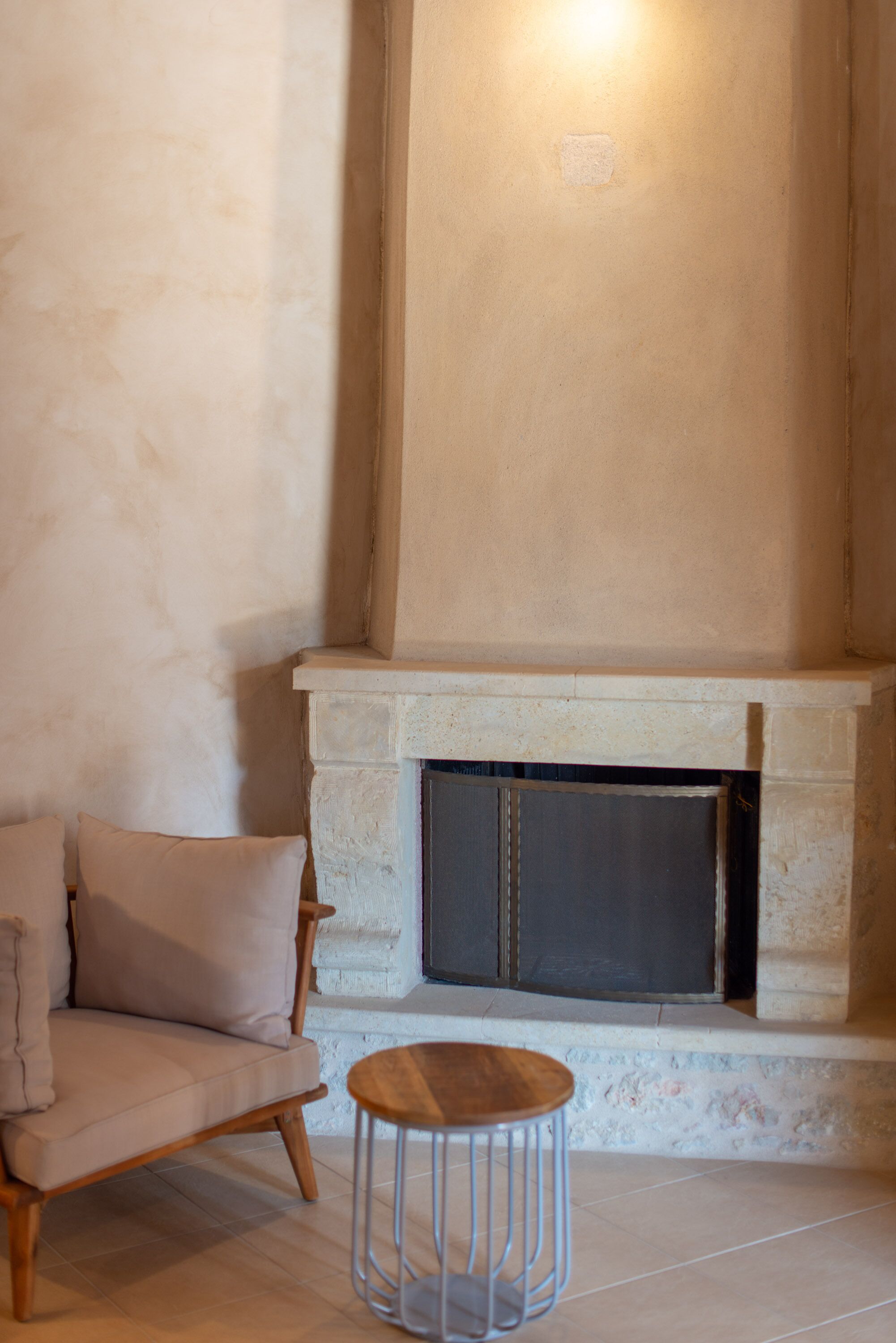 A cozy room with a fireplace, a cushioned chair, and a small round table.