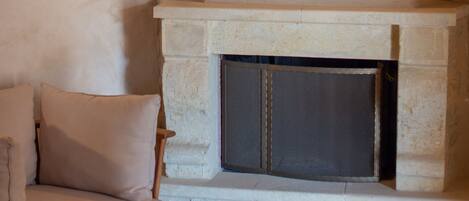 A cozy room with a fireplace, a cushioned chair, and a small round table.