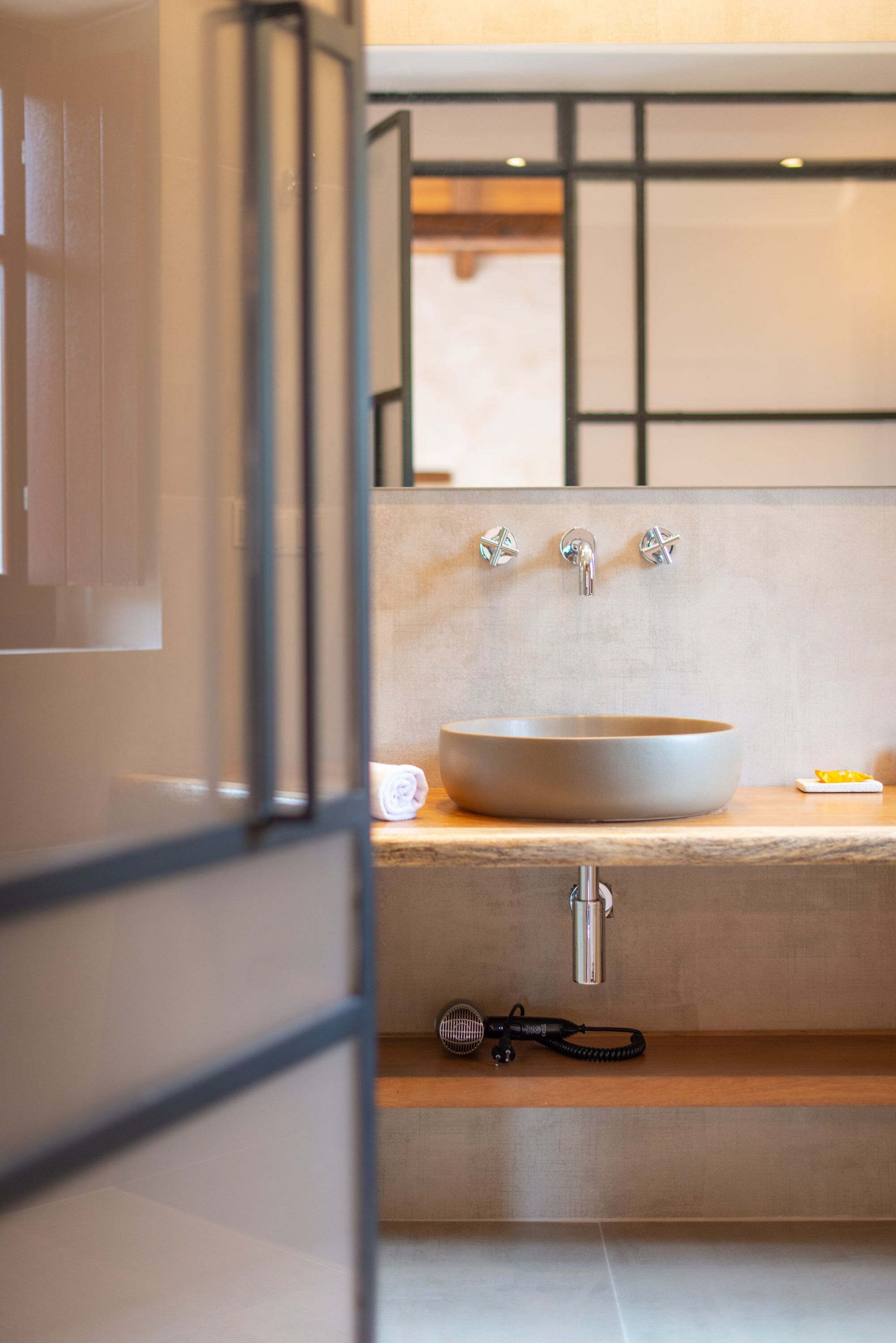 Un baño moderno con un lavamanos grande, un perchero y un secador de pelo en un estante.