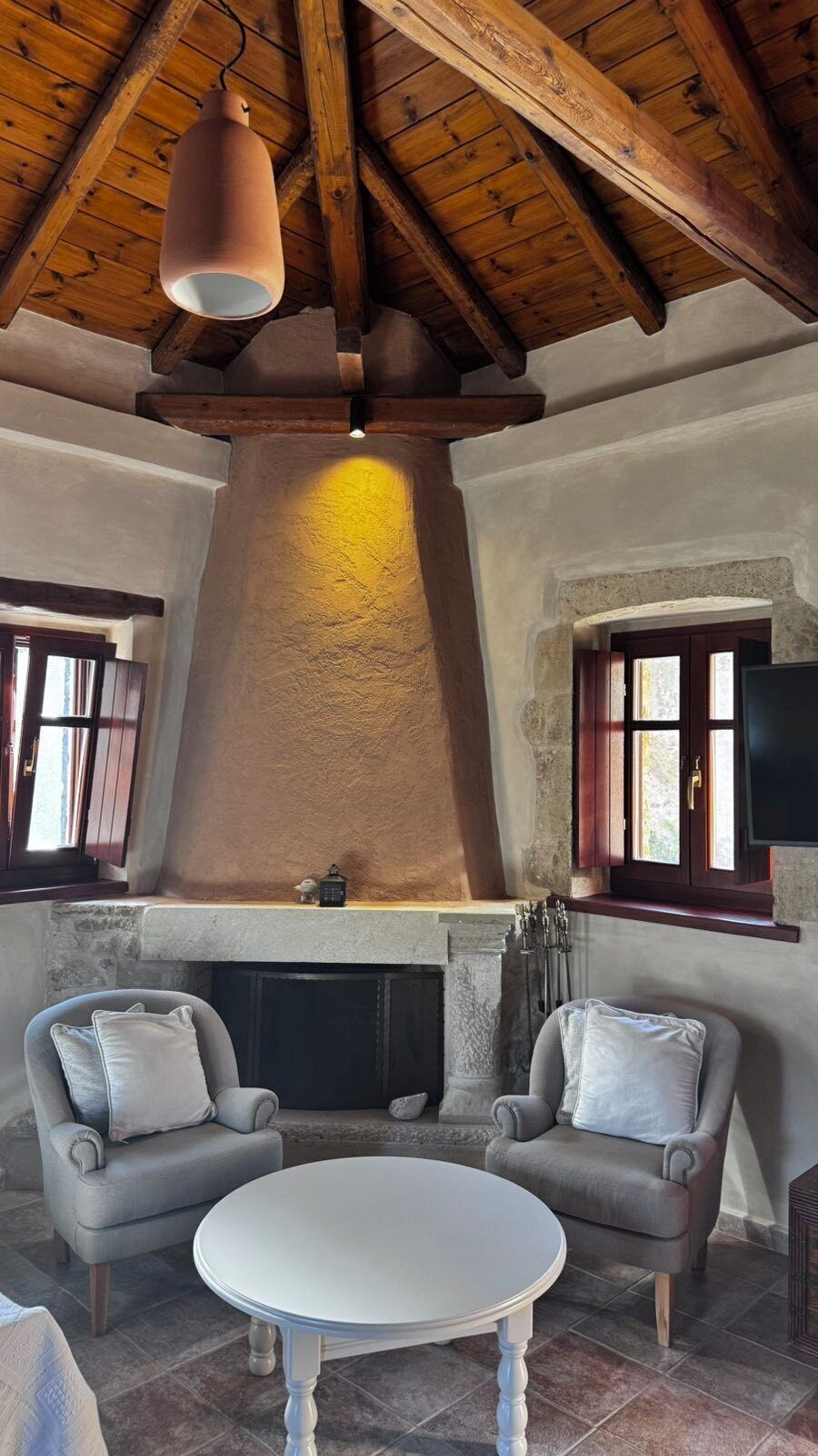 Una sala de estar acogedora con chimenea, vigas de madera en el techo y dos sillones.