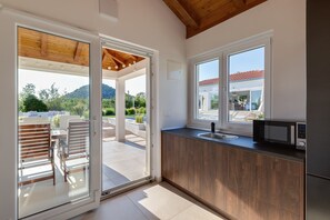 A modern kitchen with wooden cabinets, a microwave, and a large window.