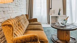 A living room with a mustard-colored sofa, a wooden coffee table, and a brick wall. - easy-flat Augarten - Apartments near Danube and Metro (Vienna)