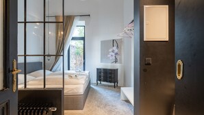 A bedroom with a bed, a dresser, a mirror, and a window with curtains. - easy-flat Augarten - Apartments near Danube and Metro (Vienna)