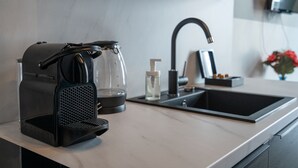 A modern kitchen with a Nespresso machine, a glass carafe, a water dispenser, and a sink. - easy-flat Augarten - Apartments near Danube and Metro (Vienna)
