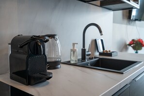 Une cuisine moderne équipée d’une machine Nespresso, d’une carafe en verre, d’un distributeur d’eau et d’un évier.