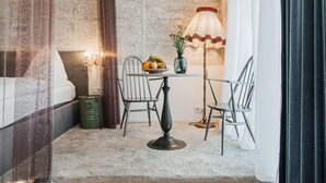 A bedroom with a bed, a table with fruit and flowers, a lamp, and a chair. - easy-flat Augarten - Apartments near Danube and Metro (Vienna)