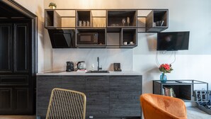 A modern kitchen with a built-in microwave, a sink, and a flat-screen TV mounted on the wall. - easy-flat Augarten - Apartments near Danube and Metro (Vienna)