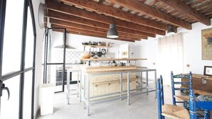 A kitchen with a central island, wooden beams on the ceiling, and a dining area with blue chairs.