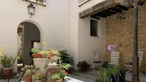 A courtyard with potted plants, a stone floor, and outdoor seating.