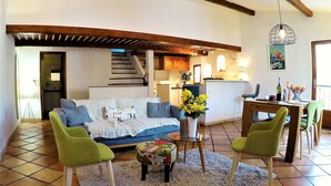 A living room with a sofa, two green chairs, a coffee table, a rug, and a dining area with a table and chairs. - Bright and large apartment in heart of the old town (Antibes)