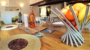 A dining table with a bottle of wine, glasses, and a fruit basket. - Bright and large apartment in heart of the old town (Antibes)