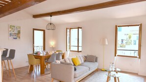 A living room with a sofa, dining table, chairs, and a glass coffee table. - Bright and large apartment in heart of the old town (Antibes)