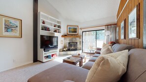 Ein gemütliches Wohnzimmer mit Kamin, Flachbildfernseher und bequemer Couch.