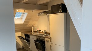 Une cuisine moderne dotée d’une verrière, d’un four encastré et de meubles de rangement blancs.