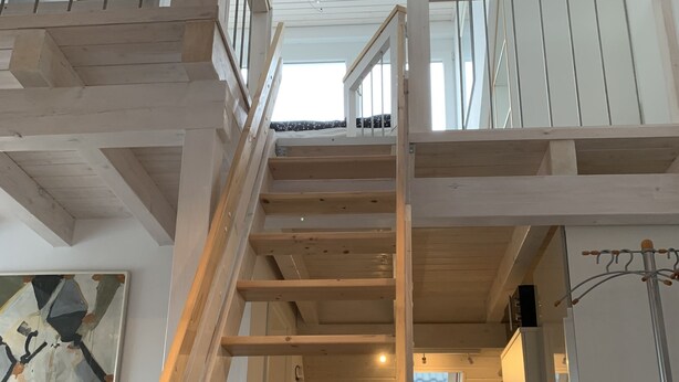 Un escalier en bois mène à une mezzanine d’où l’on peut admirer le ciel.
