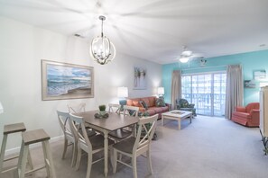 A spacious living room with a dining area, a large window with curtains, and a ceiling fan. - Beautiful Golf Villa, 2.7 Miles To Beach + Free Attraction Tickets! (North Myrtle Beach)