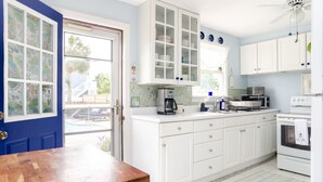 Une cuisine avec des meubles blancs, une machine à café, un four à micro-ondes et une cuisinière.
