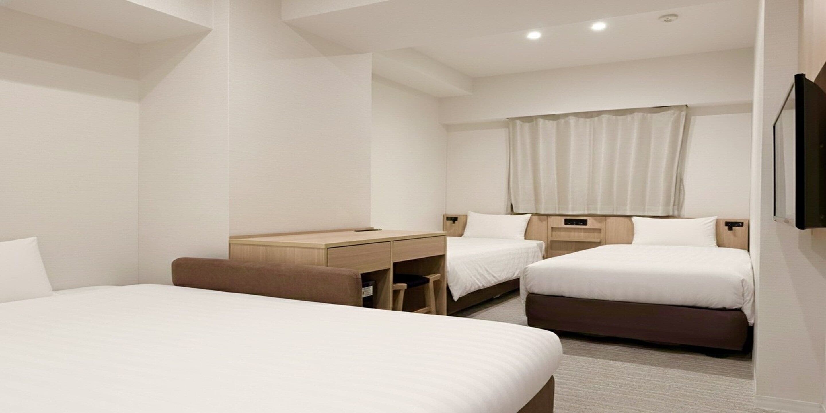 Une chambre d’hôtel avec deux lits, un bureau et une télévision.