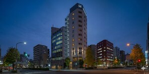 A multi-story building with a prominent corner entrance, a visible staircase, and a flat facade with evenly spaced windows. - Nesthotel alt. Kuramae Station (Tokyo)