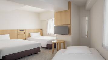 Een hotelkamer met twee bedden, een televisie, een tafeltje en een raam met gordijnen.