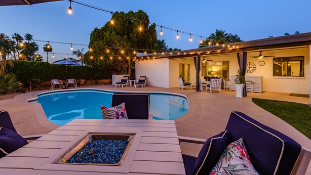 A backyard with a swimming pool, outdoor seating, string lights, and a covered patio area. - Large Pool and Entertainers Delight Yard! (Phoenix)