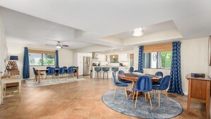 A spacious living area with a dining table, chairs, and a kitchen in the background. - Large Pool and Entertainers Delight Yard! (Phoenix)