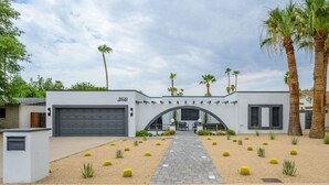 A modern house with a garage, a paved driveway, and a landscaped garden with cacti and palm trees. - Large Pool and Entertainers Delight Yard! (Phoenix)