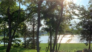 Um cenário tranquilo à beira do lago, com árvores, um caminho de cascalho e vista para a água.