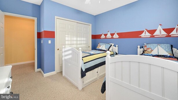 Une chambre à coucher avec un lit, une porte blanche et un ventilateur de plafond.