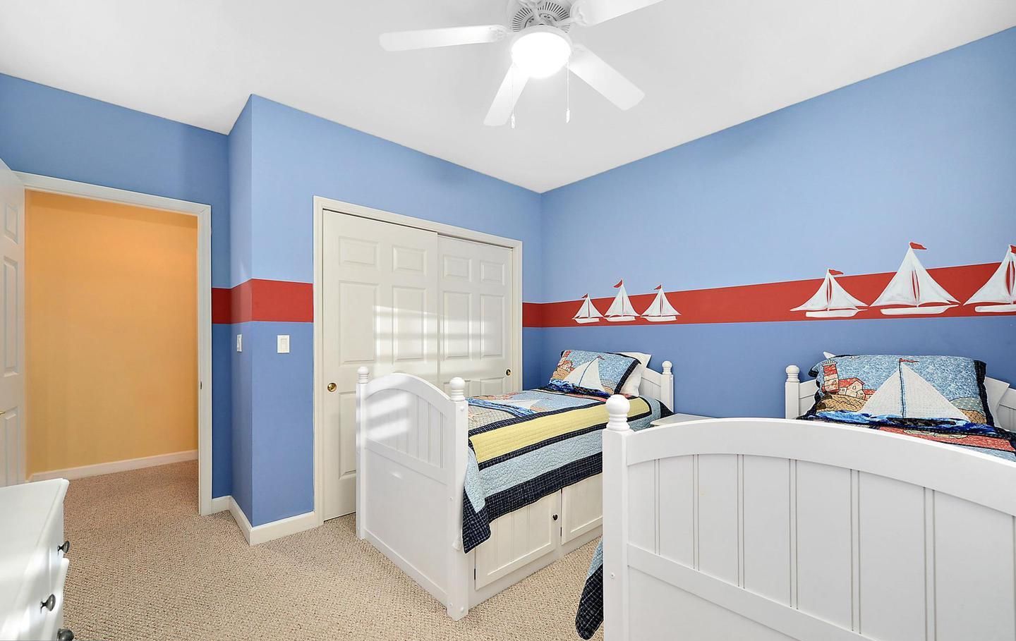 Ein Schlafzimmer mit einem Bett, einer weißen Tür und einem Deckenventilator.