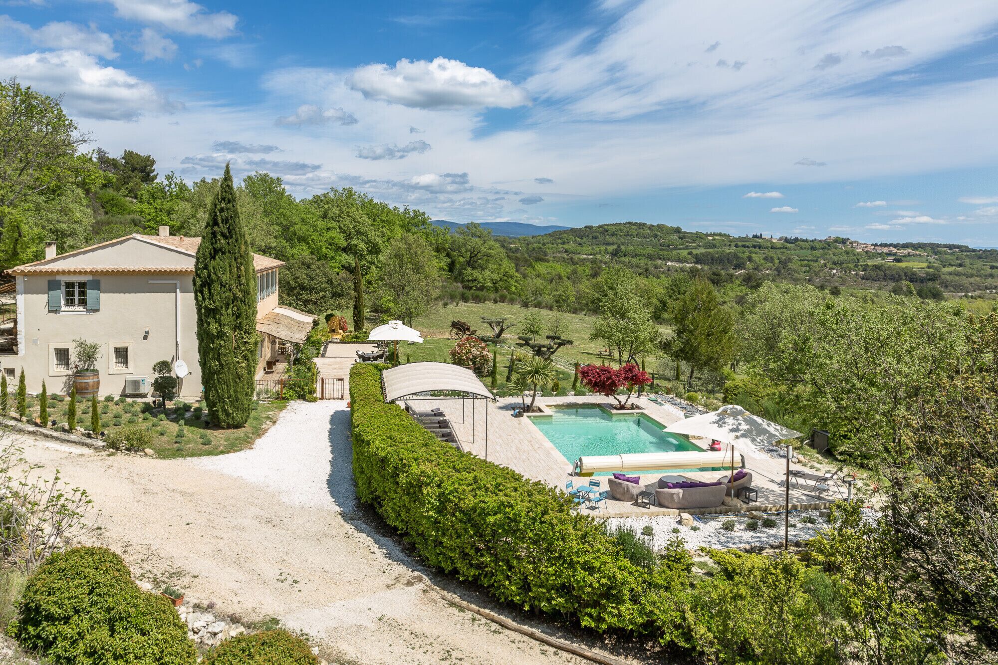 A villa with a swimming pool, outdoor seating, and a view of the surrounding countryside.